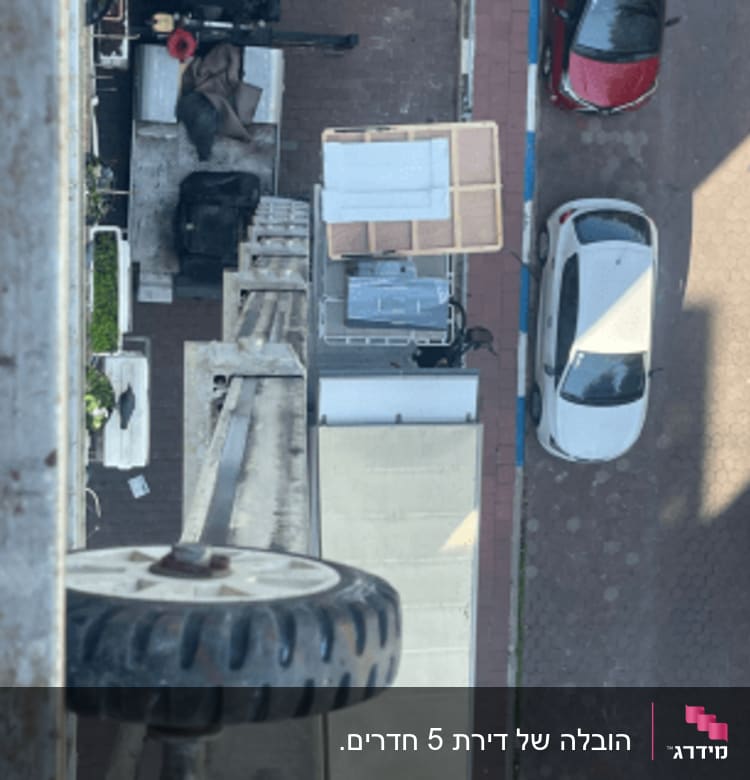 מנוף מעביר רהיטים לרכב הובלה ברחוב